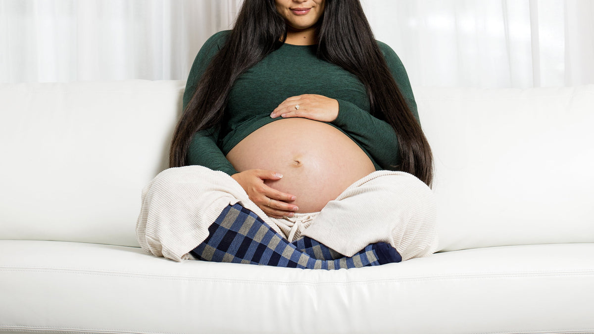 a pregnant woman wearing compression socks while sitting on a couch.