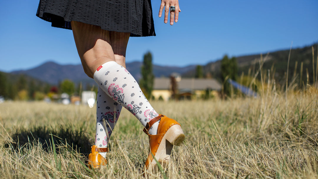 woman in grass fields wearing compression socks.