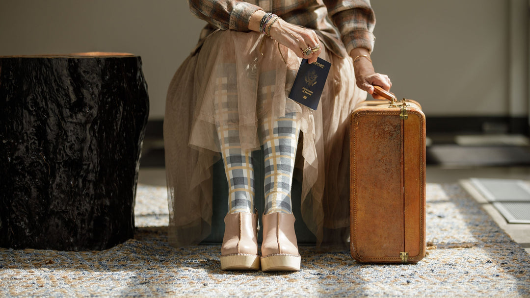 woman wearing compression socks and holding a passport & luggage bag.