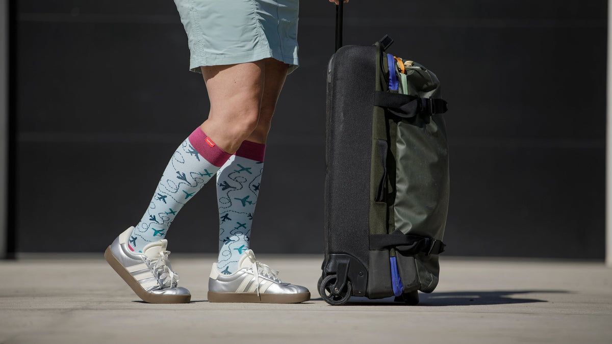 woman wearing compression socks while holding a travel bag