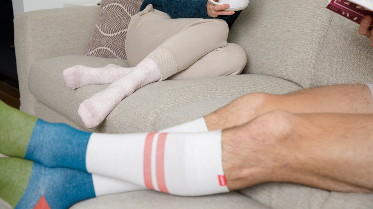 a couple sitting on a couch wearing compression socks
