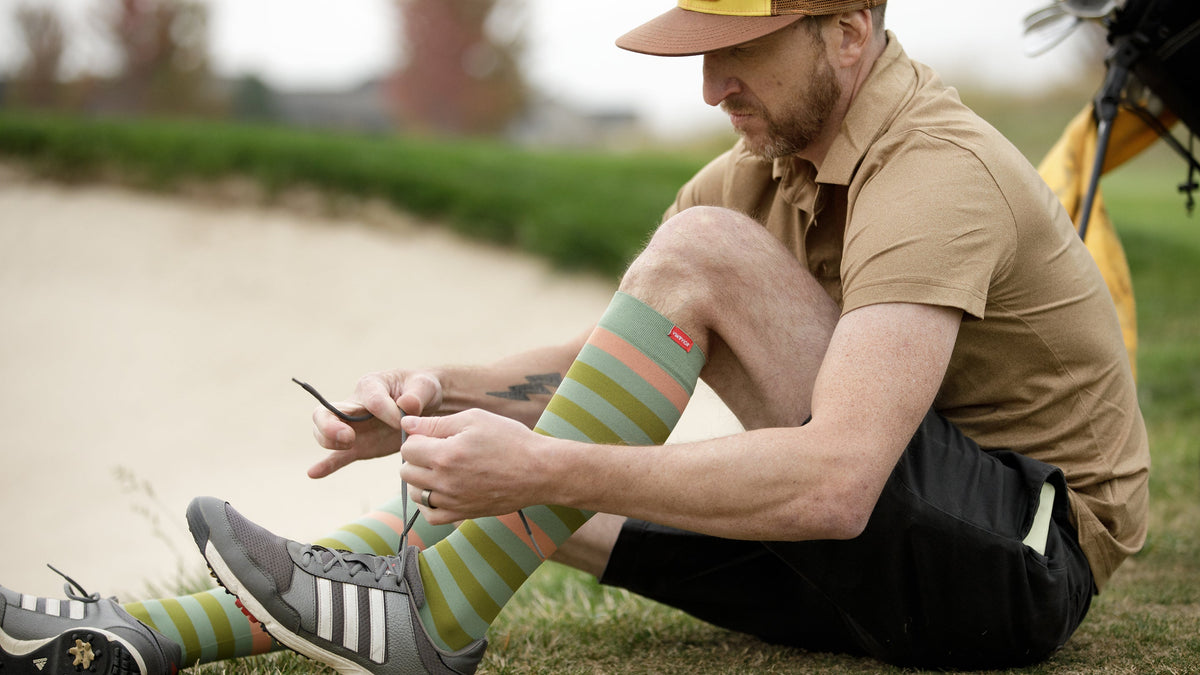 a man wearing compression socks while tying his shoes.