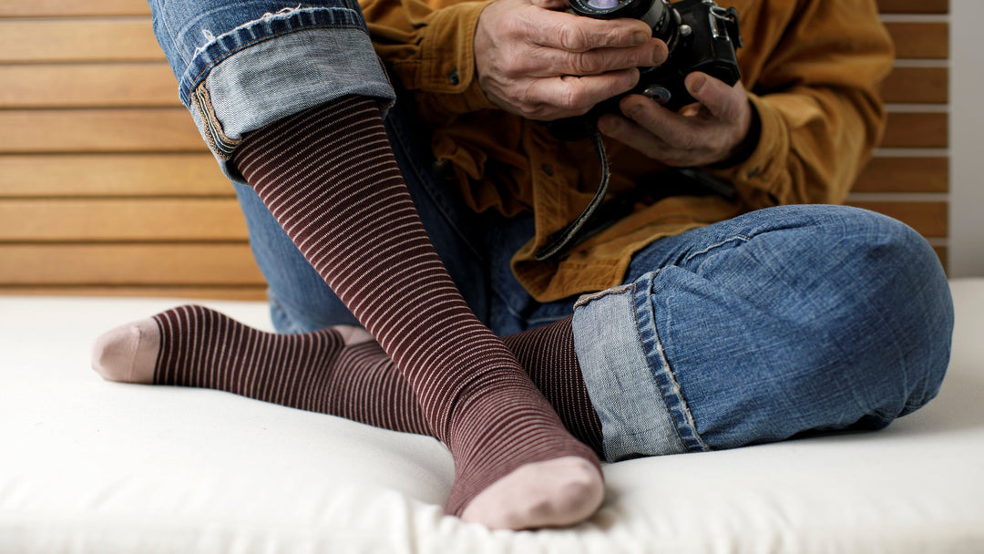 a man sitting and wearing compression socks while holding a camera