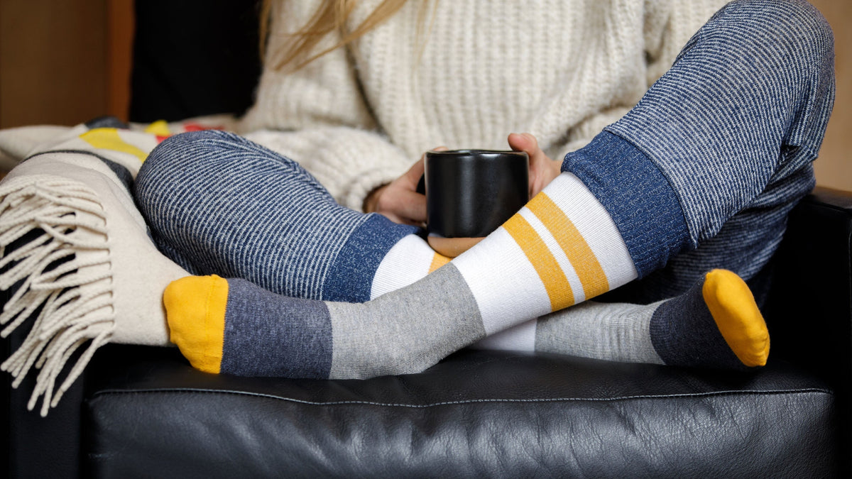 woman sitting on couch while holding a mug and wearing compression socks