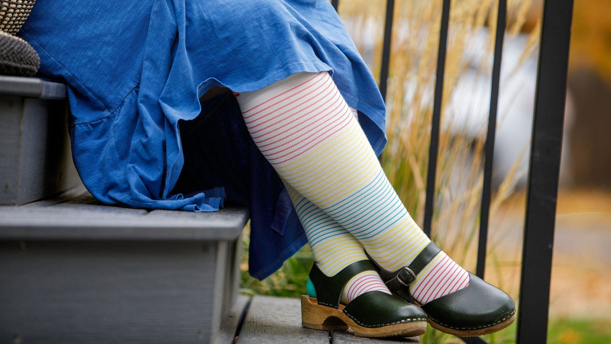 a woman wearing compression socks while sitting on  stairs