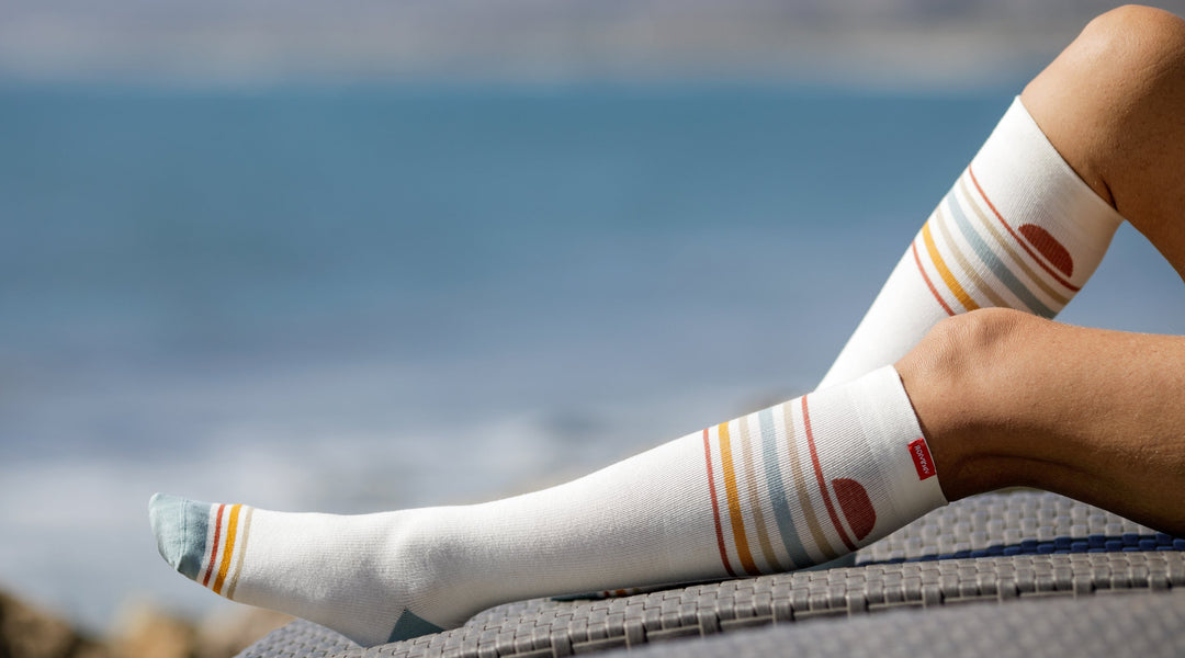 a woman wearing compression socks while  on a beach chair 