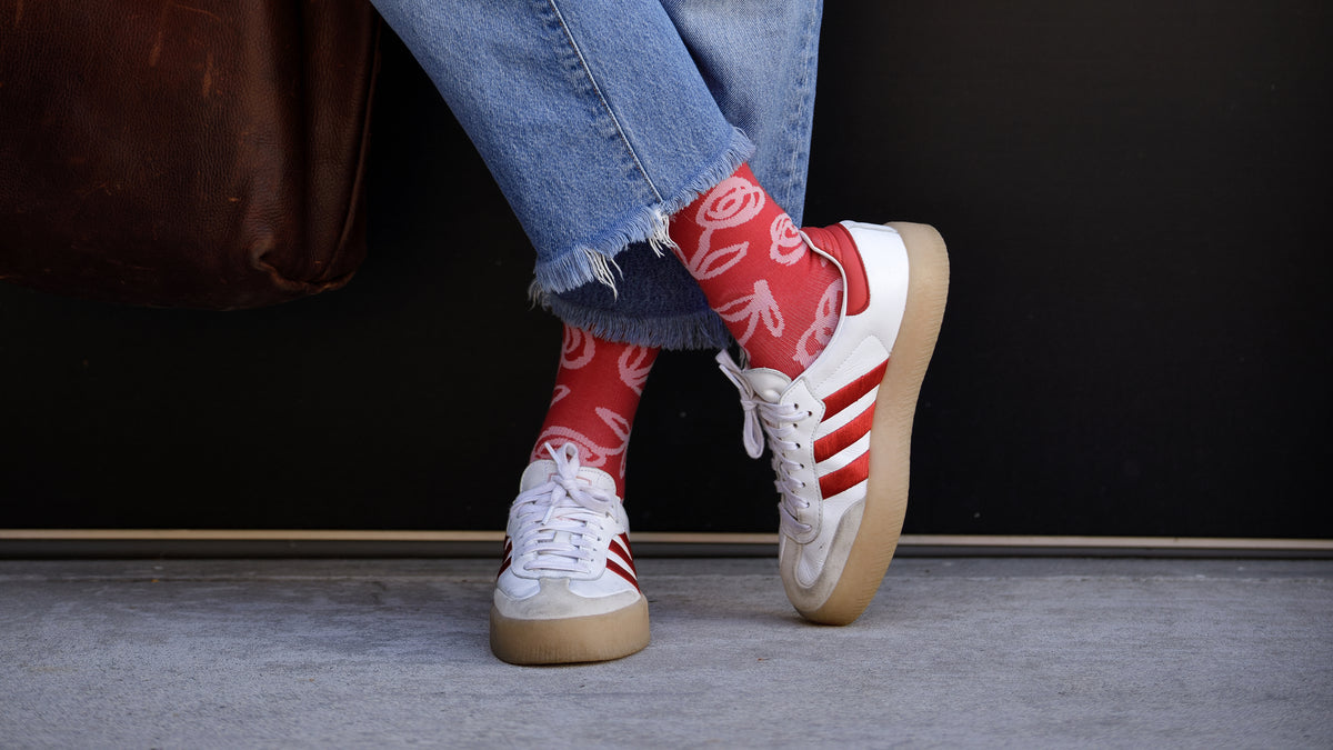 White sneakers with red accents worn with red socks featuring white patterns on a dark background