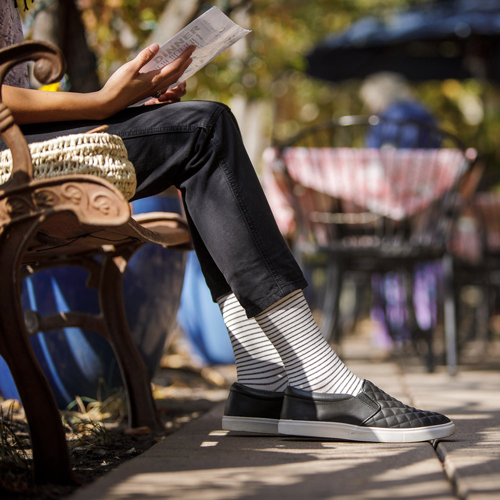 woman sitting outside wearing 30-40 mmHg: Pinstripe Cream & Black (Cotton) Compression Socks